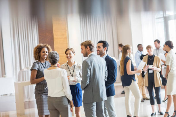 group of business people standing in hall, smiling and talking together - 会议 個照片及圖片檔