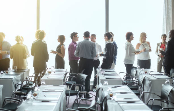 group of people standing by windows of conference room, socializing during coffee break - 会议 個照片及圖片檔